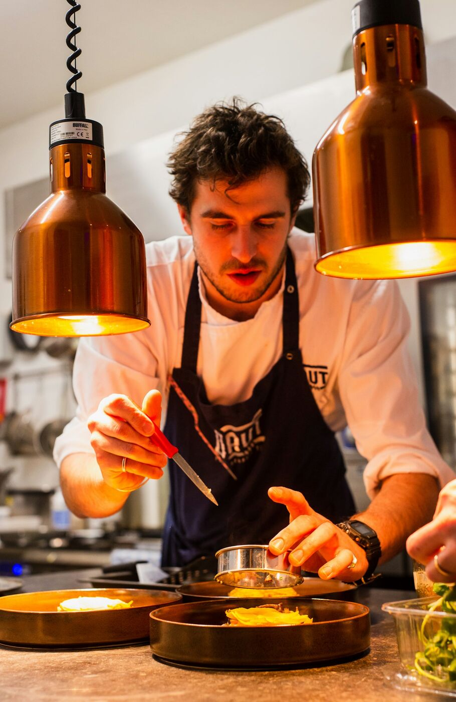 A private chef plating a dish under warm copper lamps